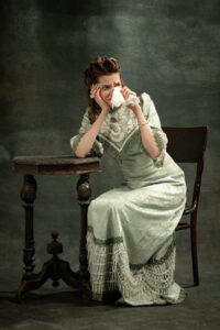 mujer con ropa victoriana limpiándose las lágrimas con un pañuelo